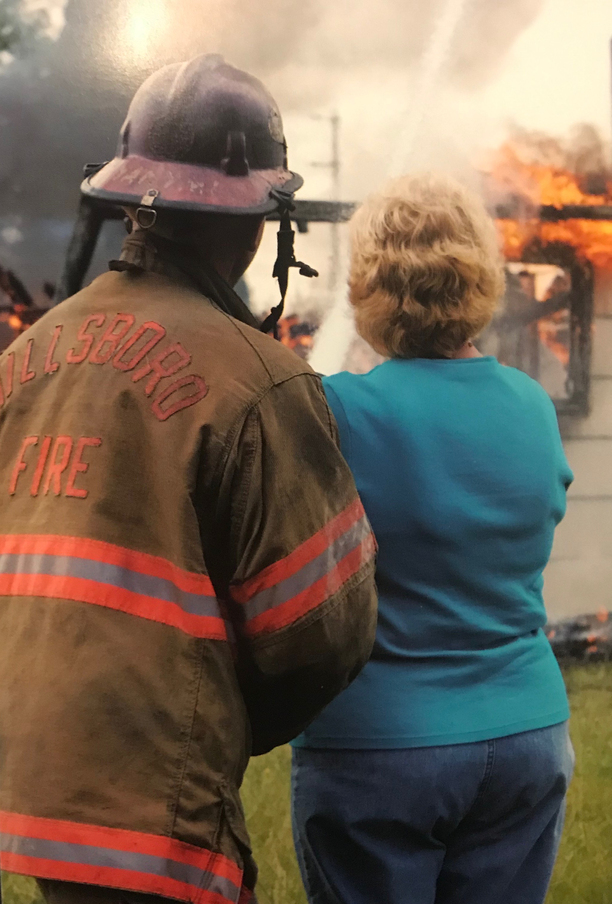 Old Woman and fire fighter putting out houses fire